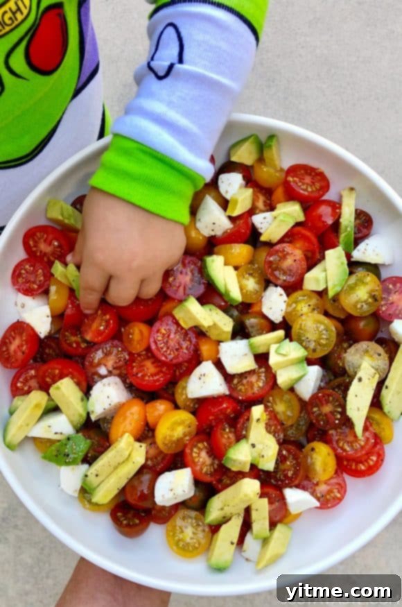 Fun and Healthy Food Creations for Kids 2 A white bowl containing cherry tomatoes and avocado with a little boy's hand reaching into it