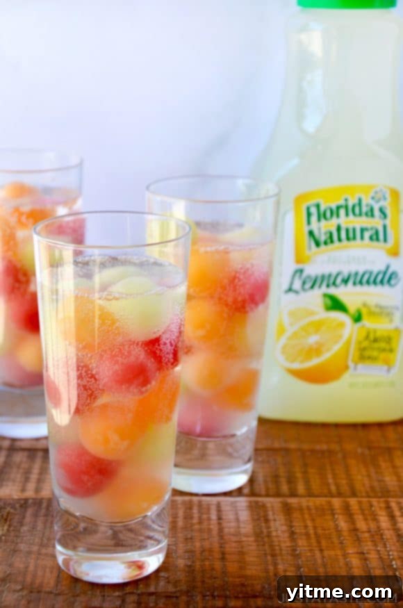 Clear cocktail glasses with melon balls and a bottle of lemonade