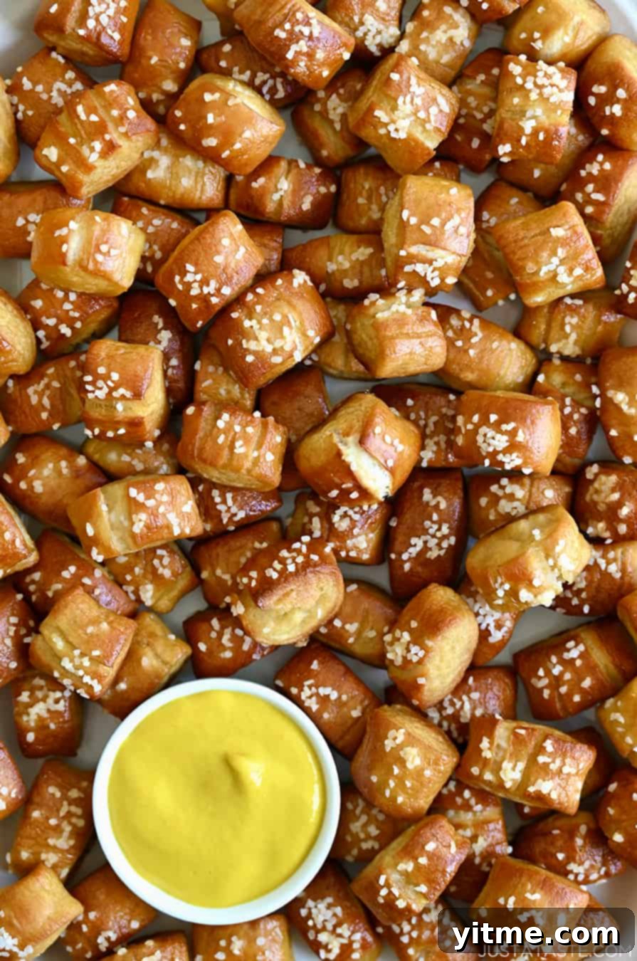A close-up view of Easy Homemade Soft Pretzel Bites surrounding a small ramekin filled with yellow mustard