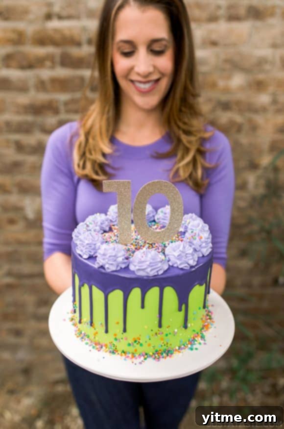 A vibrant purple and green drip cake adorned with colorful sprinkles, with a girl in the background holding it up with joy. A symbol of celebration for Just a Taste's anniversary.