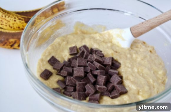 Sour Cream Chocolate Chunk Banana Bread batter with chocolate chunks and spatula