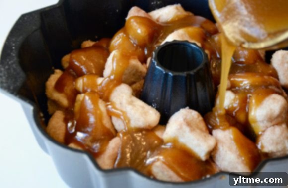 Butter mixture being poured on top of monkey bread pieces in bundt pan