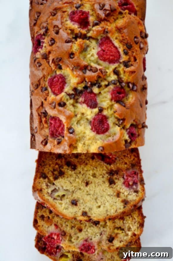 A top-down view of a loaf of Raspberry Chocolate Chip Banana Bread cut into slices, showcasing the texture and ingredients.