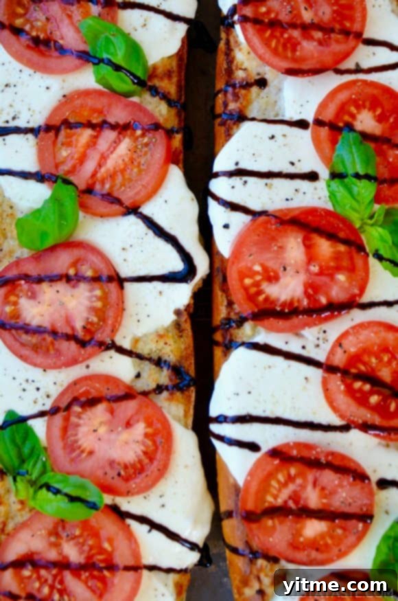 Fresh Caprese Garlic Bread 3 A top down view of two halves of Caprese Garlic Bread drizzled with balsamic syrup
