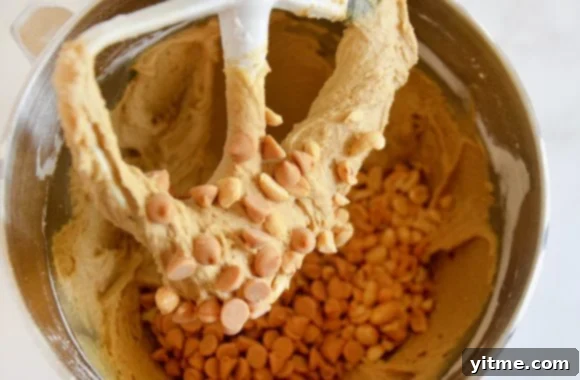 A close-up view of the peanut butter blondies batter in a stand mixer, highlighting the incorporation of peanut butter chips and chopped peanuts.