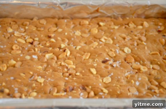 A close-up view of a foil-lined baking sheet with freshly baked Double Peanut Butter Blondies, ready for slicing and serving.