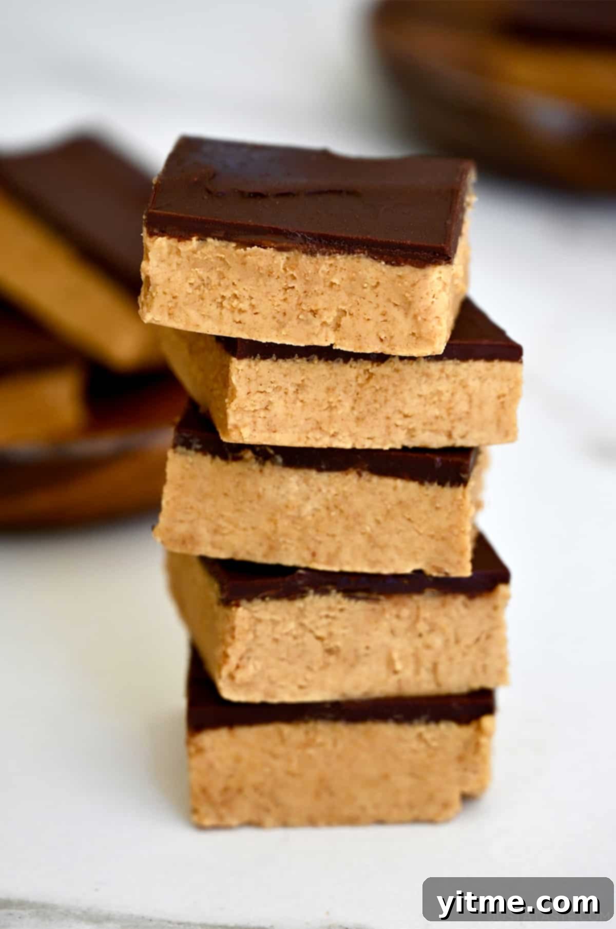 A delicious stack of no-bake peanut butter bars with a smooth chocolate topping.