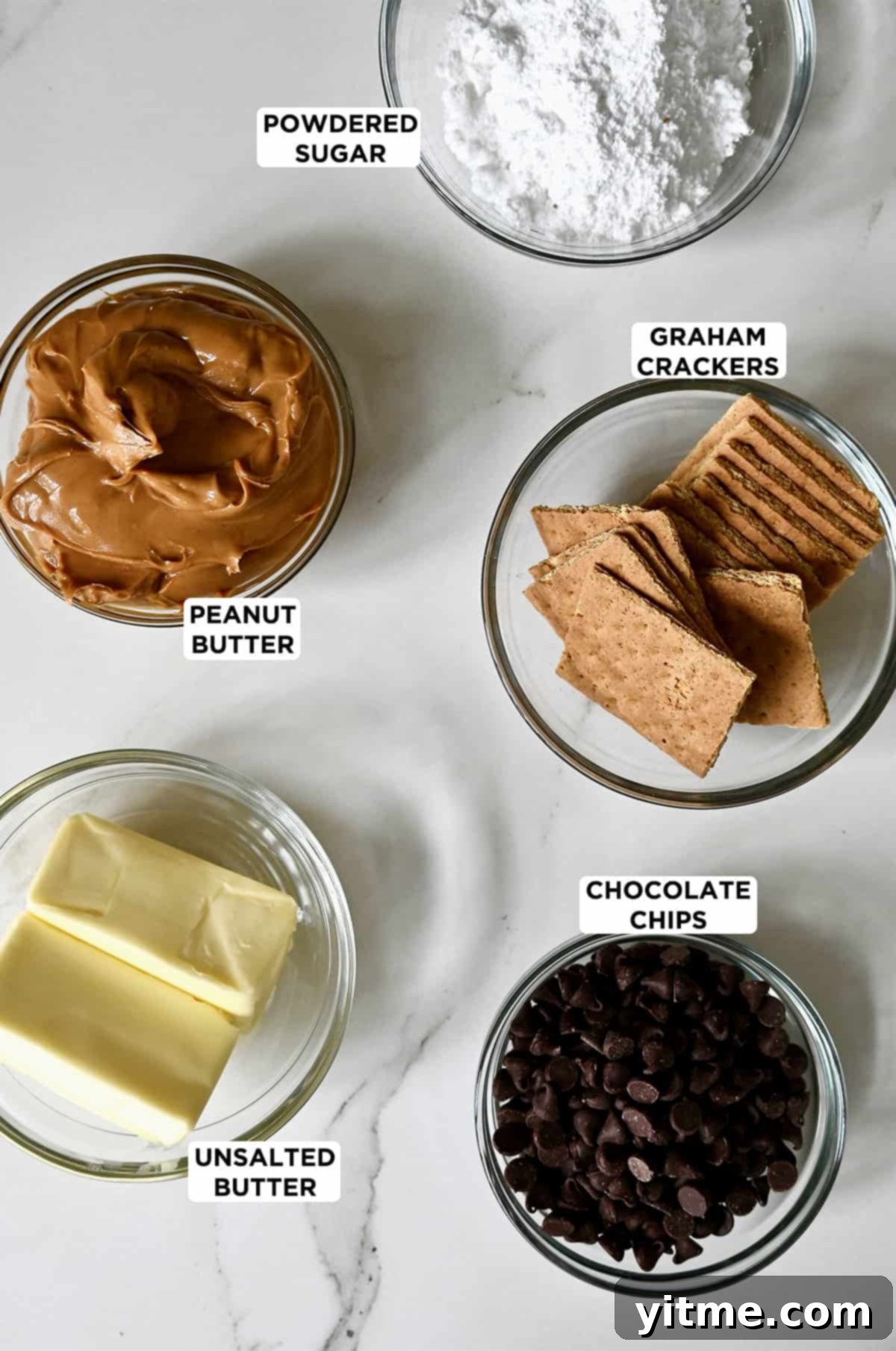 The ingredients needed to make no-bake peanut butter bars: butter, peanut butter, powdered sugar, graham crackers, and chocolate chips.