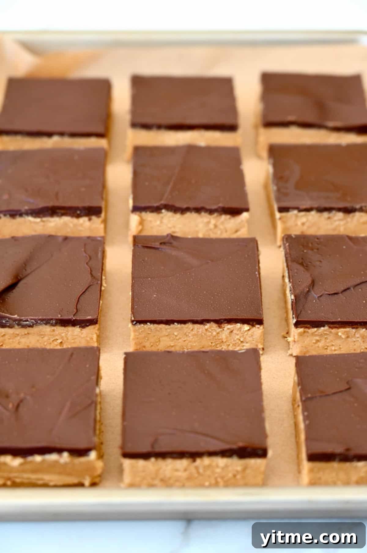 Perfectly sliced chocolate peanut butter bars arranged on a baking sheet.