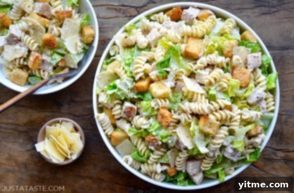 A top down view of a large bowl and a small bowl containing Chicken Caesar Pasta Salad