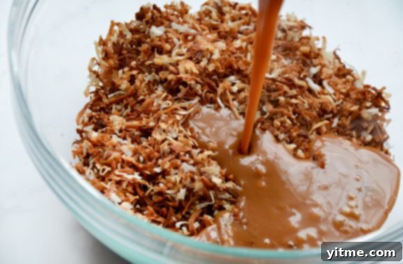 Samoa Dream Cake 8 Glass bowl containing toasted coconut with melted caramel being poured on top
