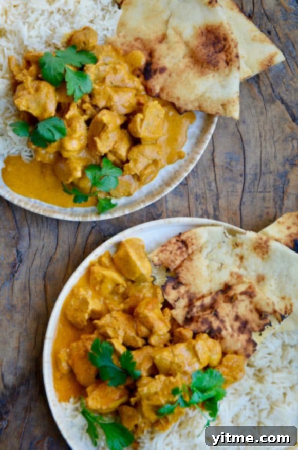 Irresistible Chicken Tikka Masala 6 Two plates containing The Best Chicken Tikka Masala with cilantro, white rice and naan