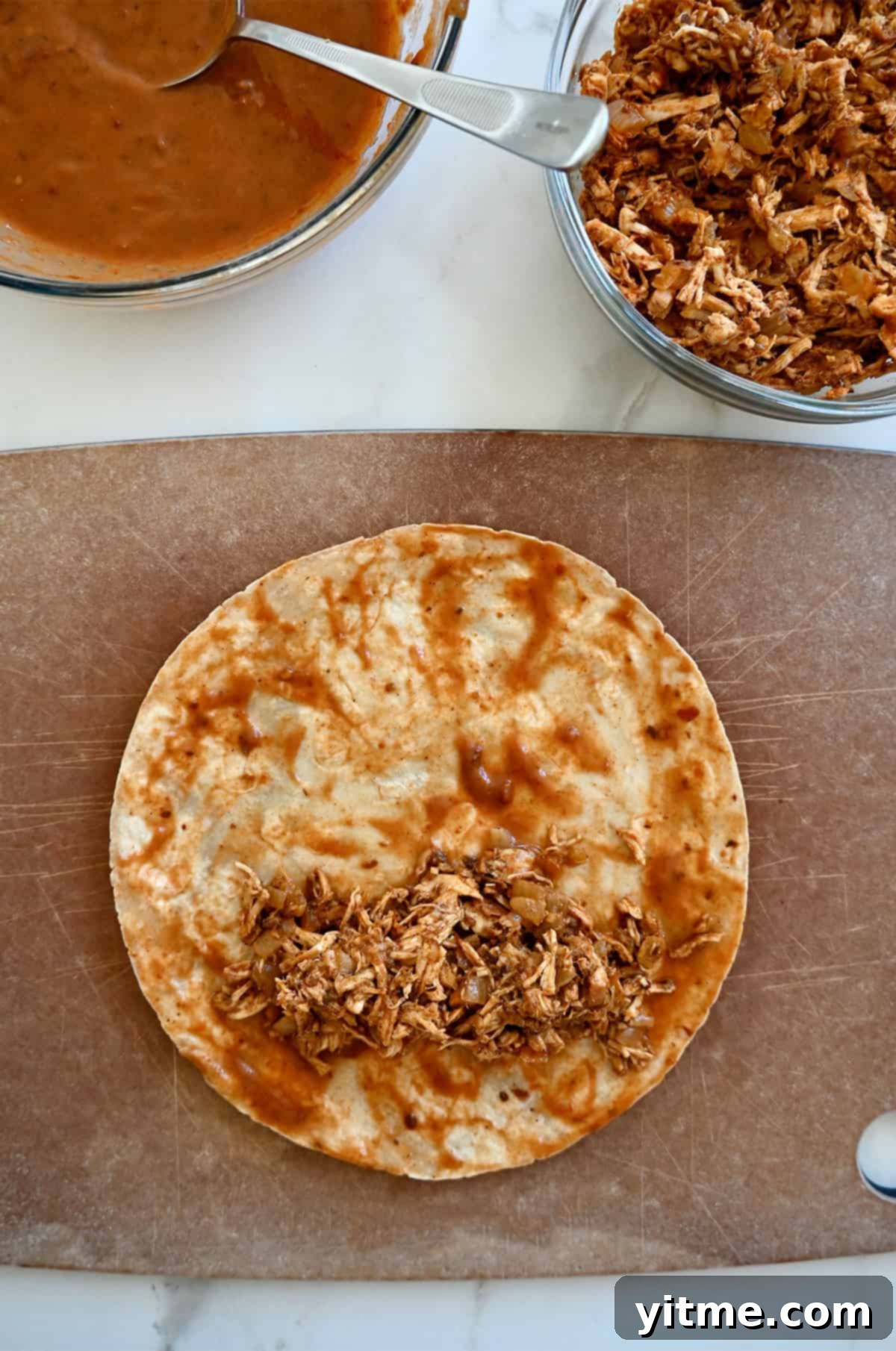 Weeknight Rotisserie Chicken Enchiladas 6 Shredded chicken filling atop a tortilla that's been dipped into enchilada sauce.