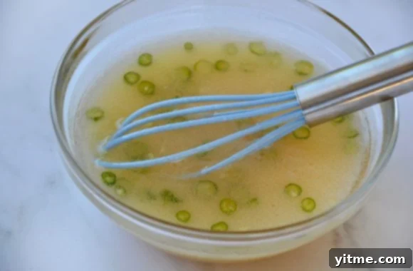 A glass bowl containing a whisk and the vibrant, freshly made lime dressing.