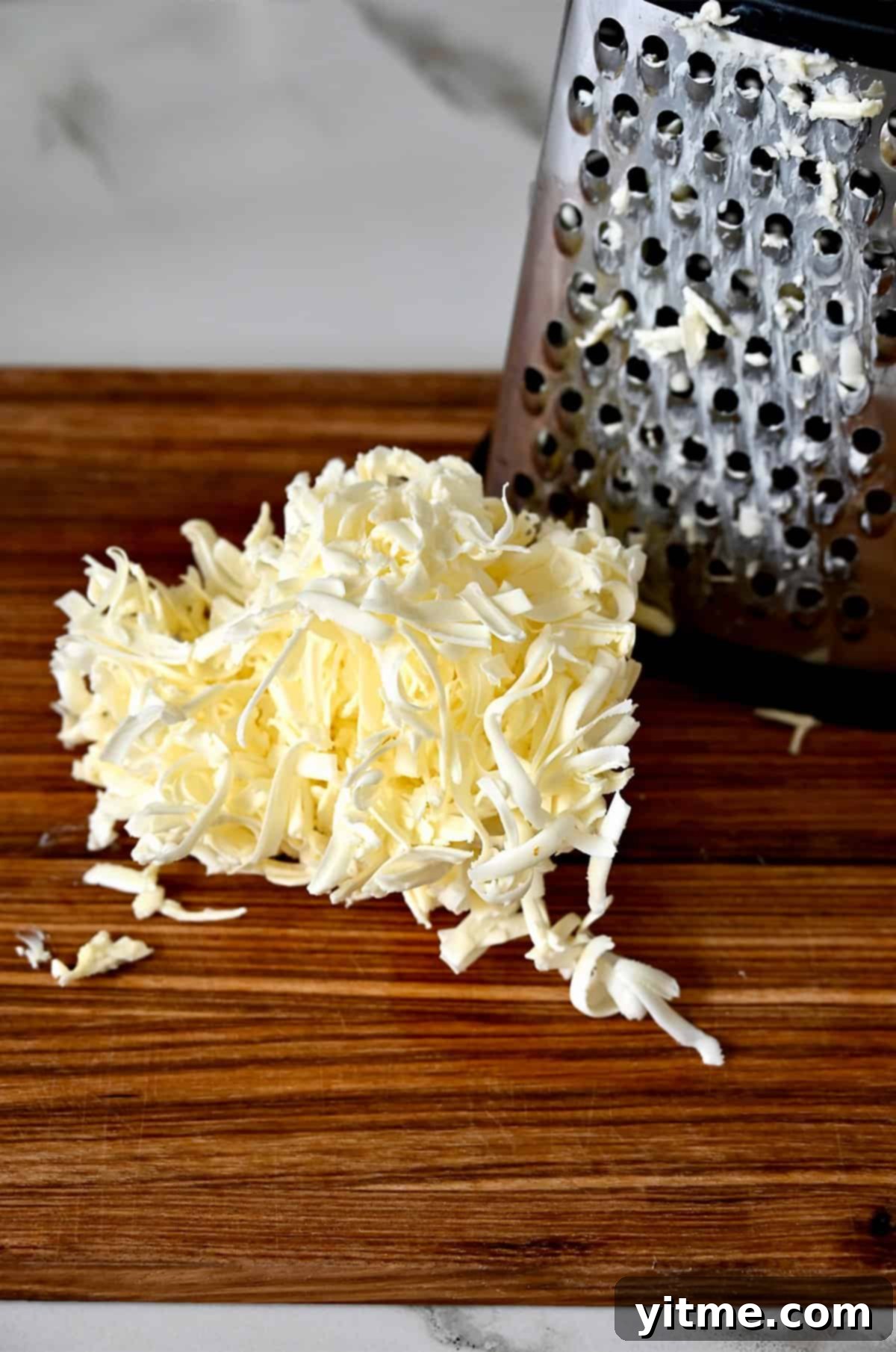 Grated butter on a cutting board next to a box grater.