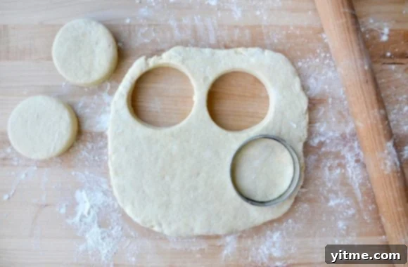 Cutting board and rolling pin next to biscuit dough