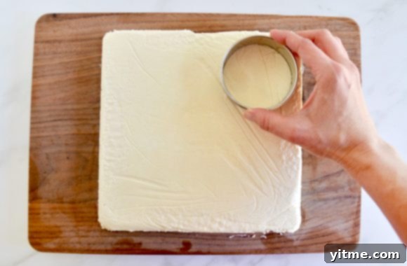 Quick Lemon Ice Cream Sandwiches 5 A wood cutting board containing a sheet of ice cream being cut out with a circular cookie cutter