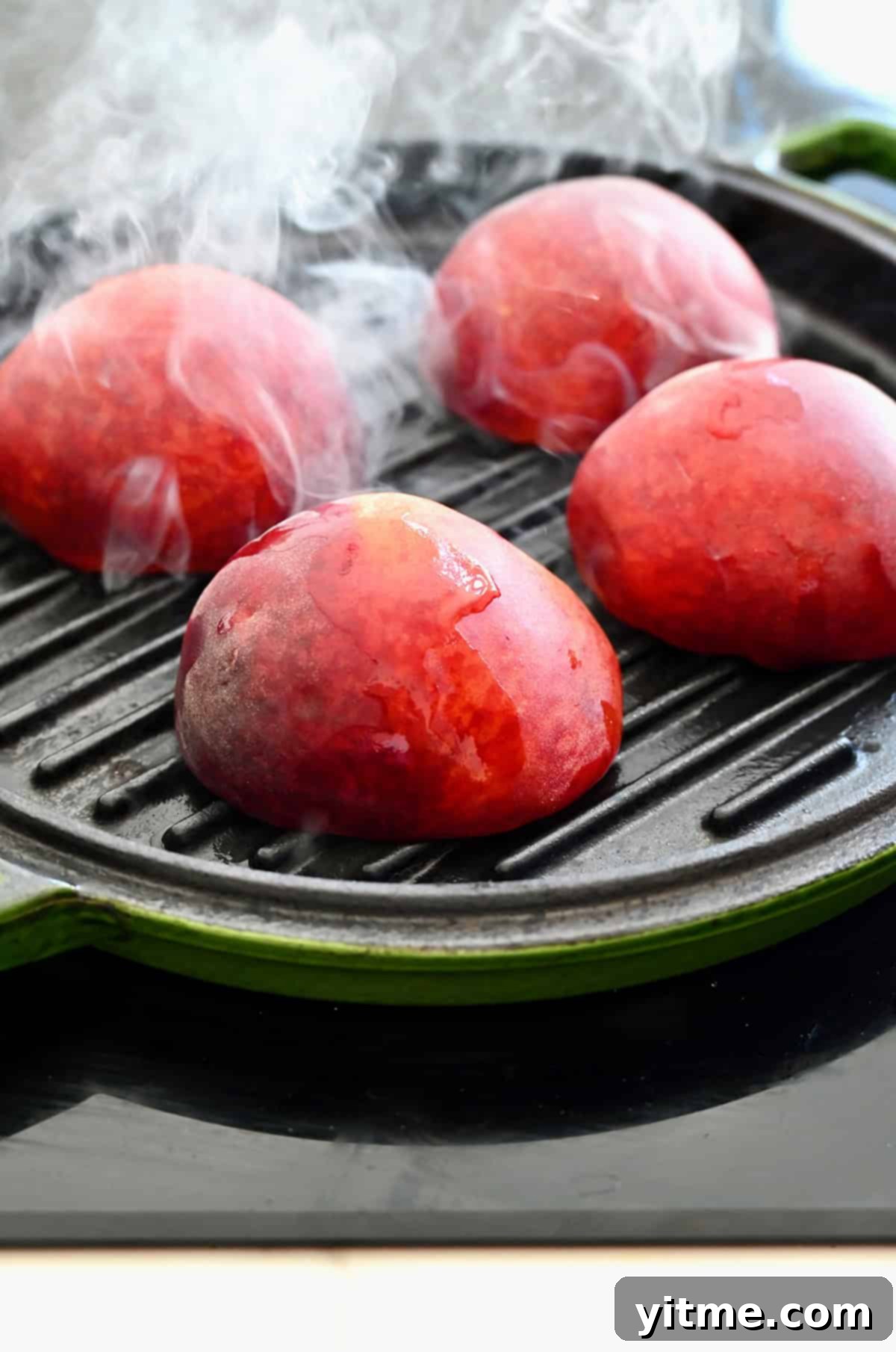 Peaches grilling cut-side down on a grill pan.