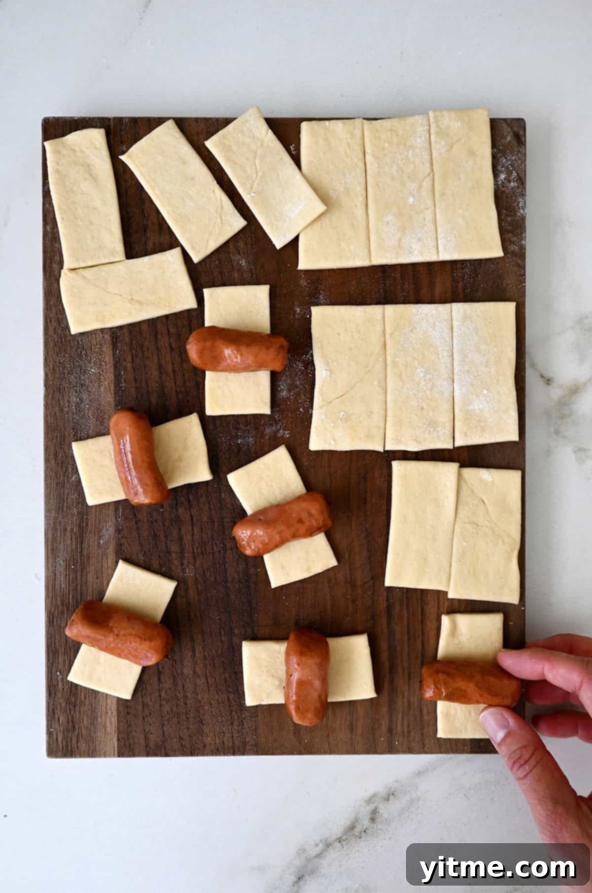 Wrapping Little Smokies in strips of crescent roll dough.