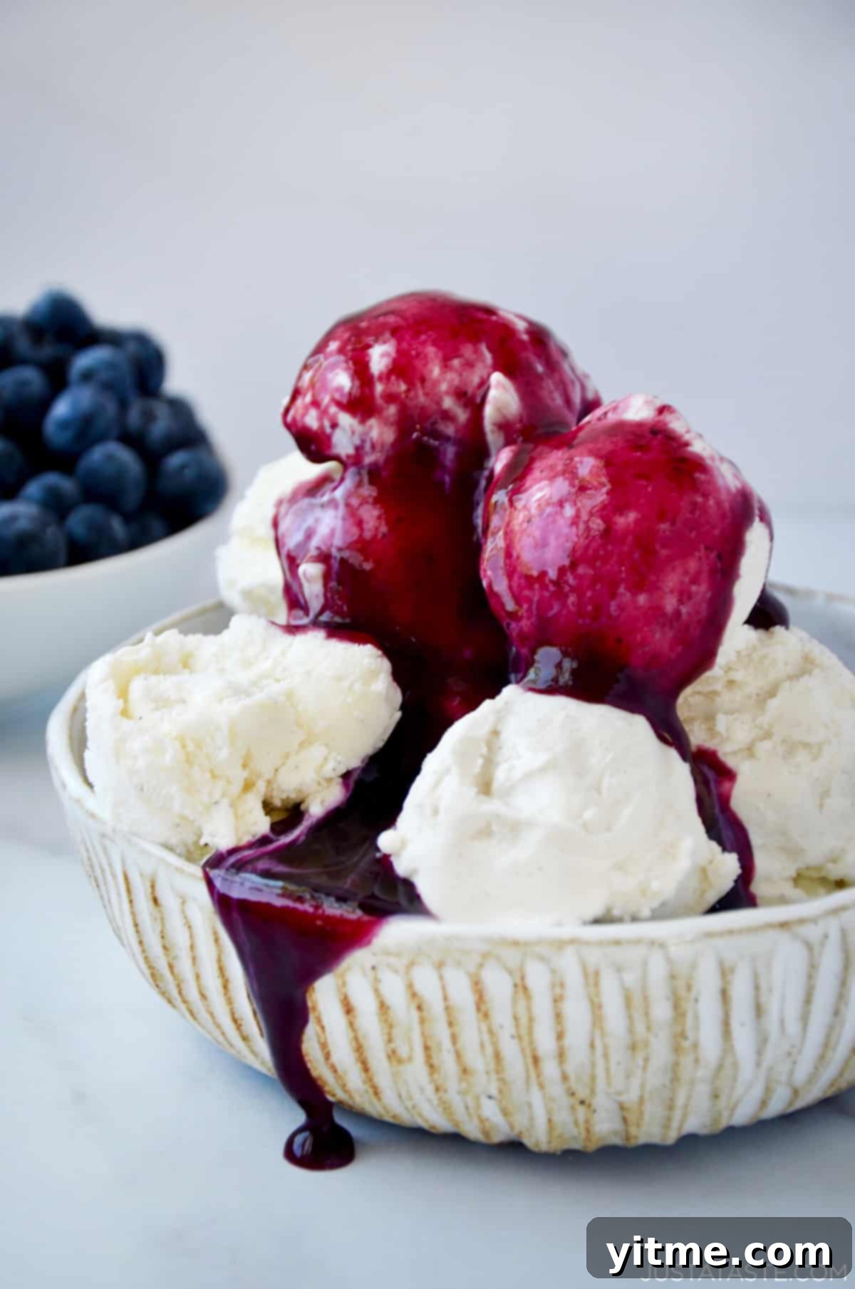 Blueberry sauce poured over vanilla ice cream in a bowl.