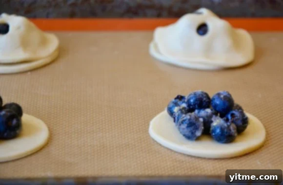 Effortless Blueberry Mini Pies 6 Blueberry hand pies unbaked and being assembled