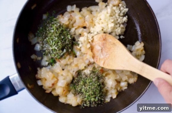 Golden Tomato and Sweet Onion Cheese Tart 4 Wooden spoon stirring caramelized onions, minced garlic and fresh herbs in sauce pan
