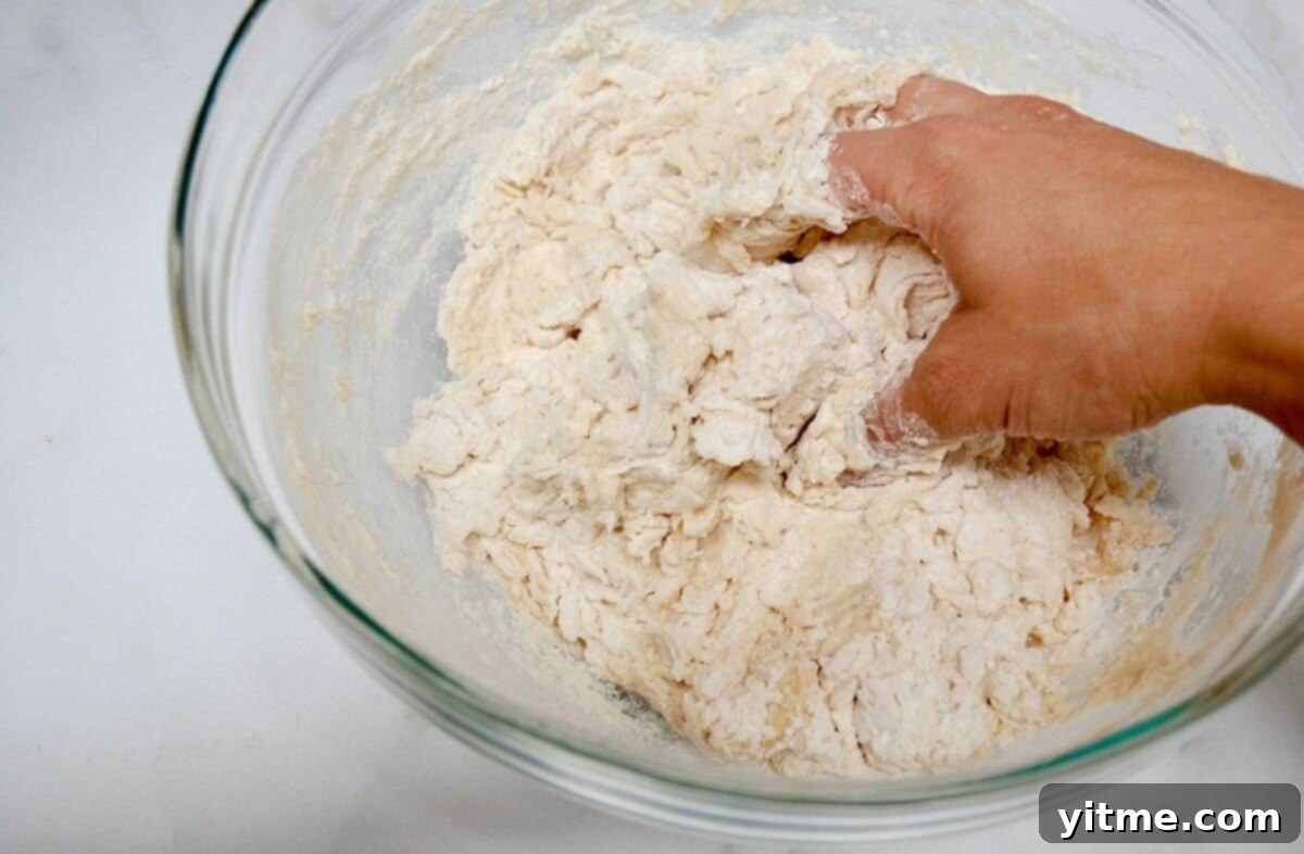 Mixing tortilla dough by hand in a glass bowl.