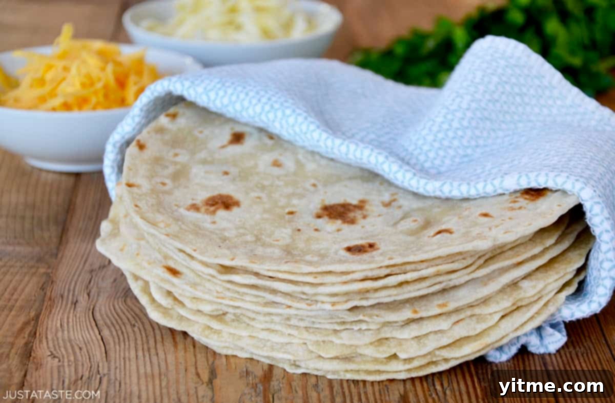 A stack of homemade flour tortillas in a blue towel.