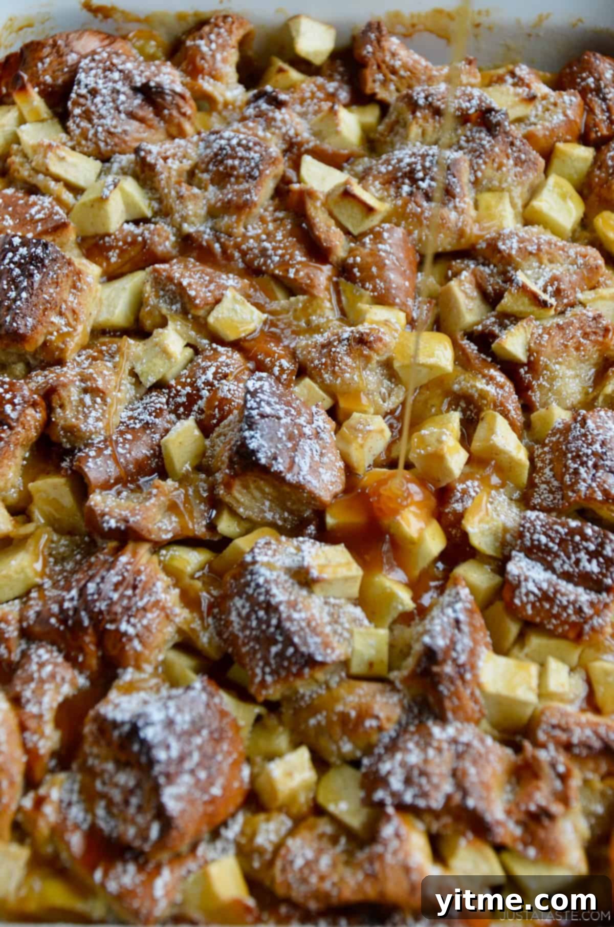 Caramel sauce is being drizzled atop freshly baked apple pudding.