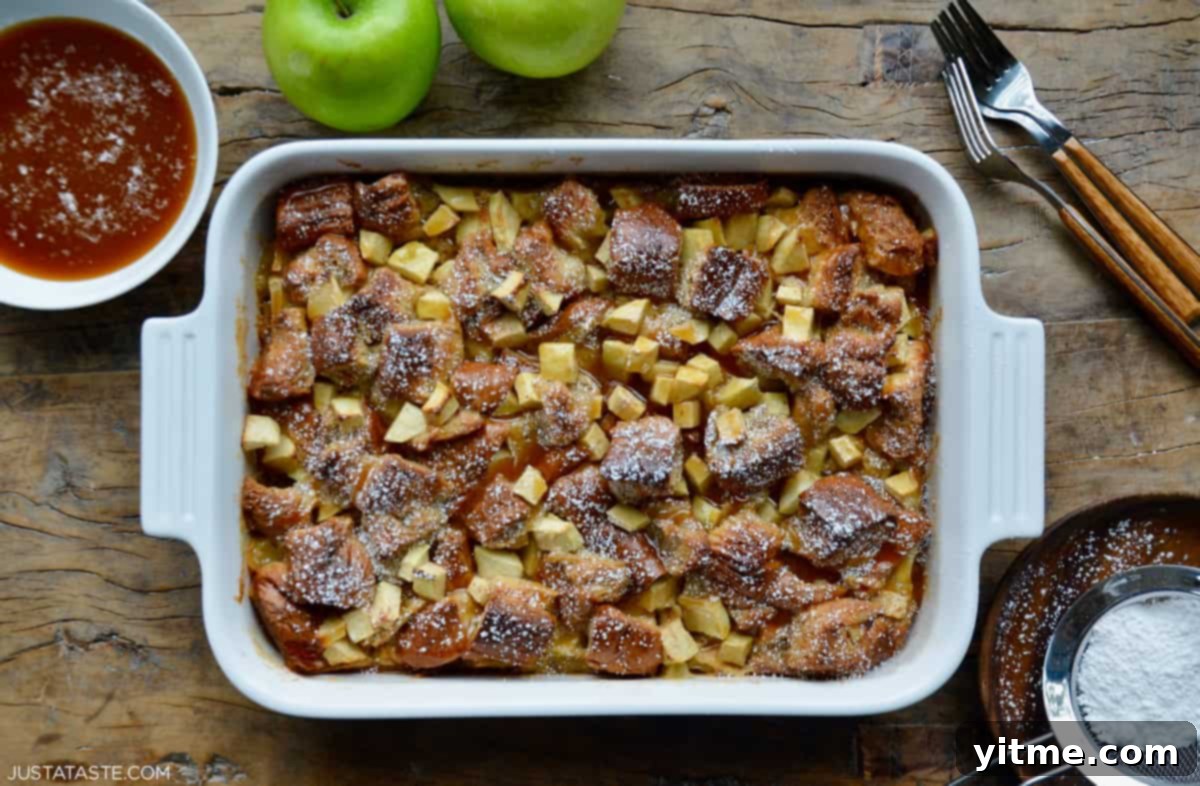 Apple bread pudding baked with brioche and Granny Smith apples in a white 9x13 baking dish, finished with a drizzle of bourbon caramel sauce.