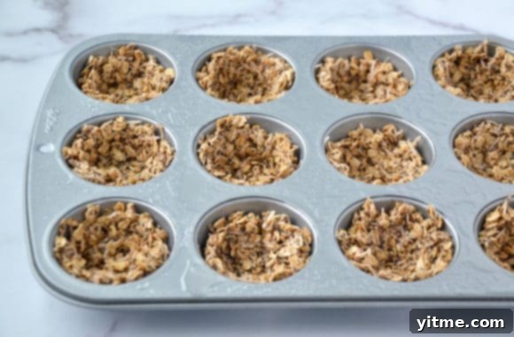 Closeup of muffin tin with unbaked granola mixture pressed into cups
