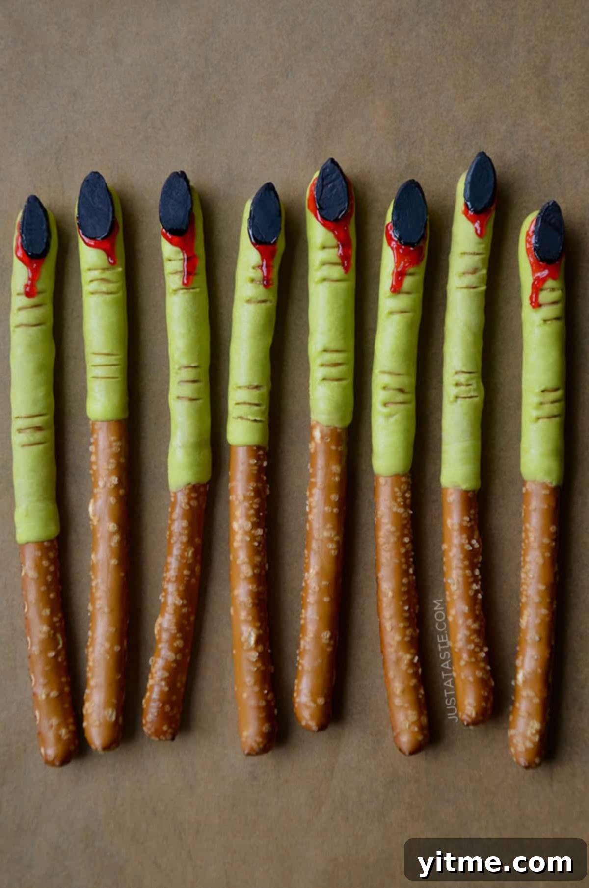 Witches finger pretzels - pretzel rods dipped into green candy melts with almond 'fingernails' that are 'bleeding'.