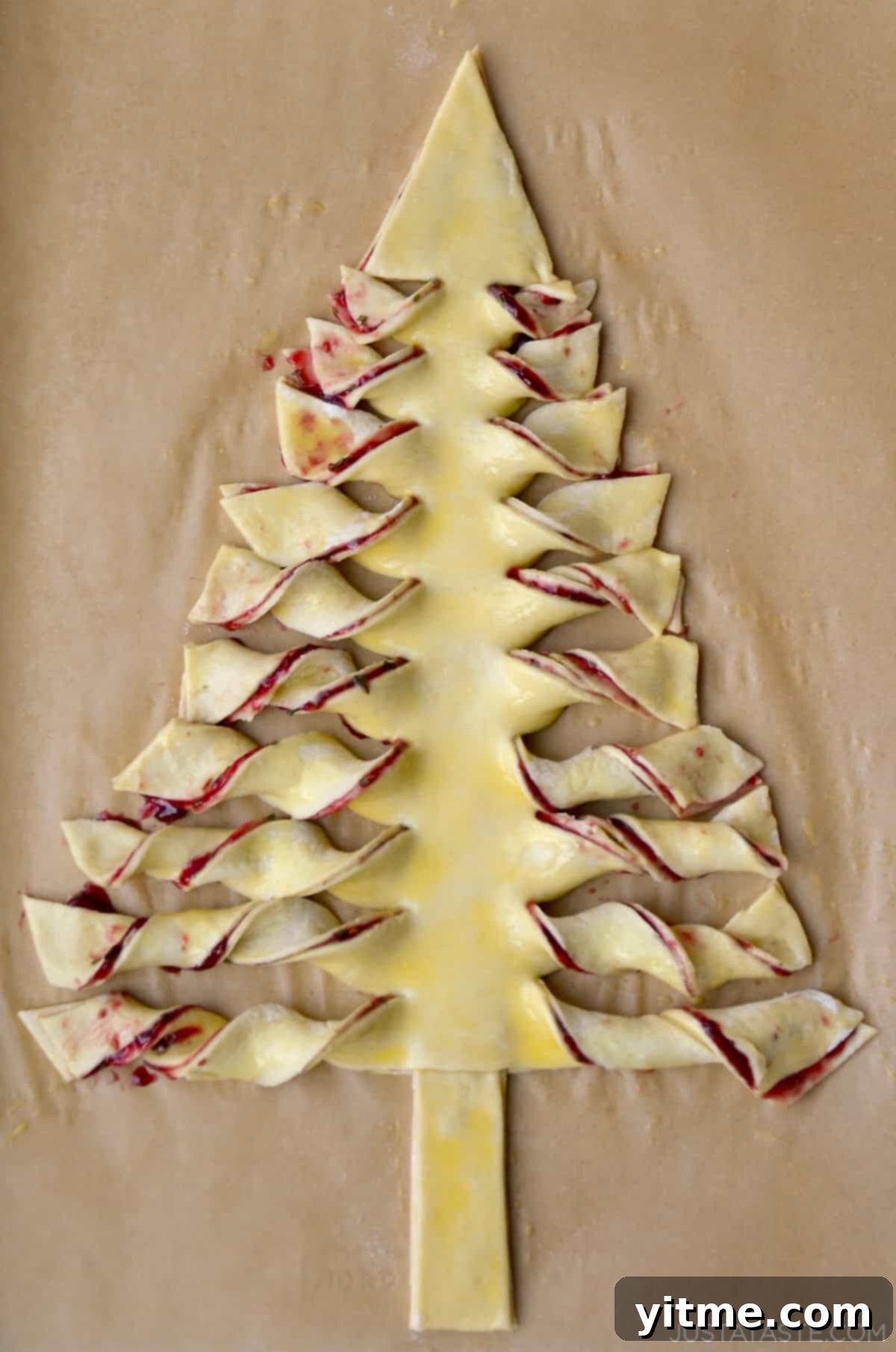 Puff pastry Christmas tree on parchment paper lined baking sheet.