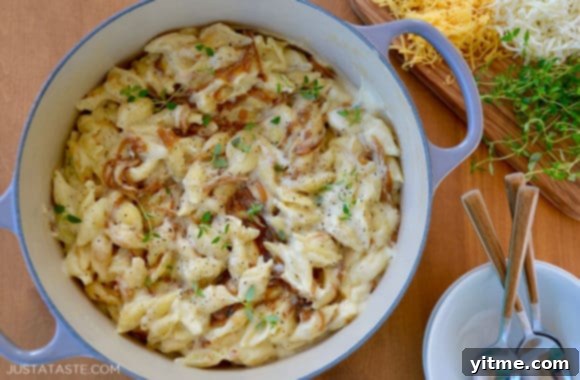 A pot with mac and cheese surrounded by shredded cheese and fresh thyme