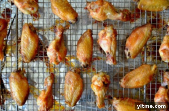 Chicken wings arranged on a baking rack placed over foil, showing the browned and crispy exterior.
