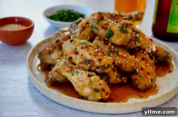 A serving of sticky sesame chicken wings garnished with cilantro and sesame seeds, ready to be devoured.