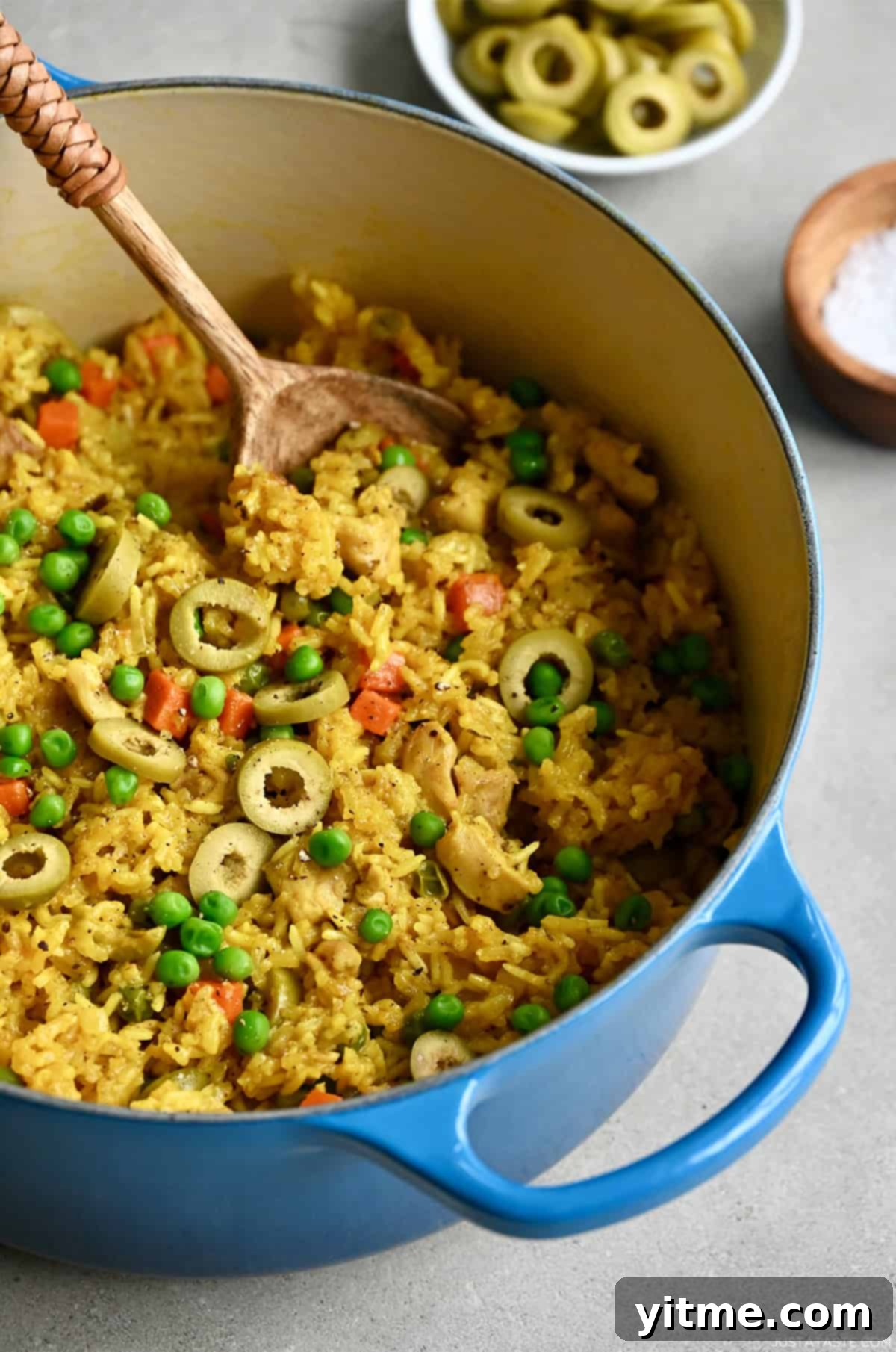 One-Pot Chicken and Yellow Rice Cuban-style with peas, carrots, onions and green olives in a Dutch oven.