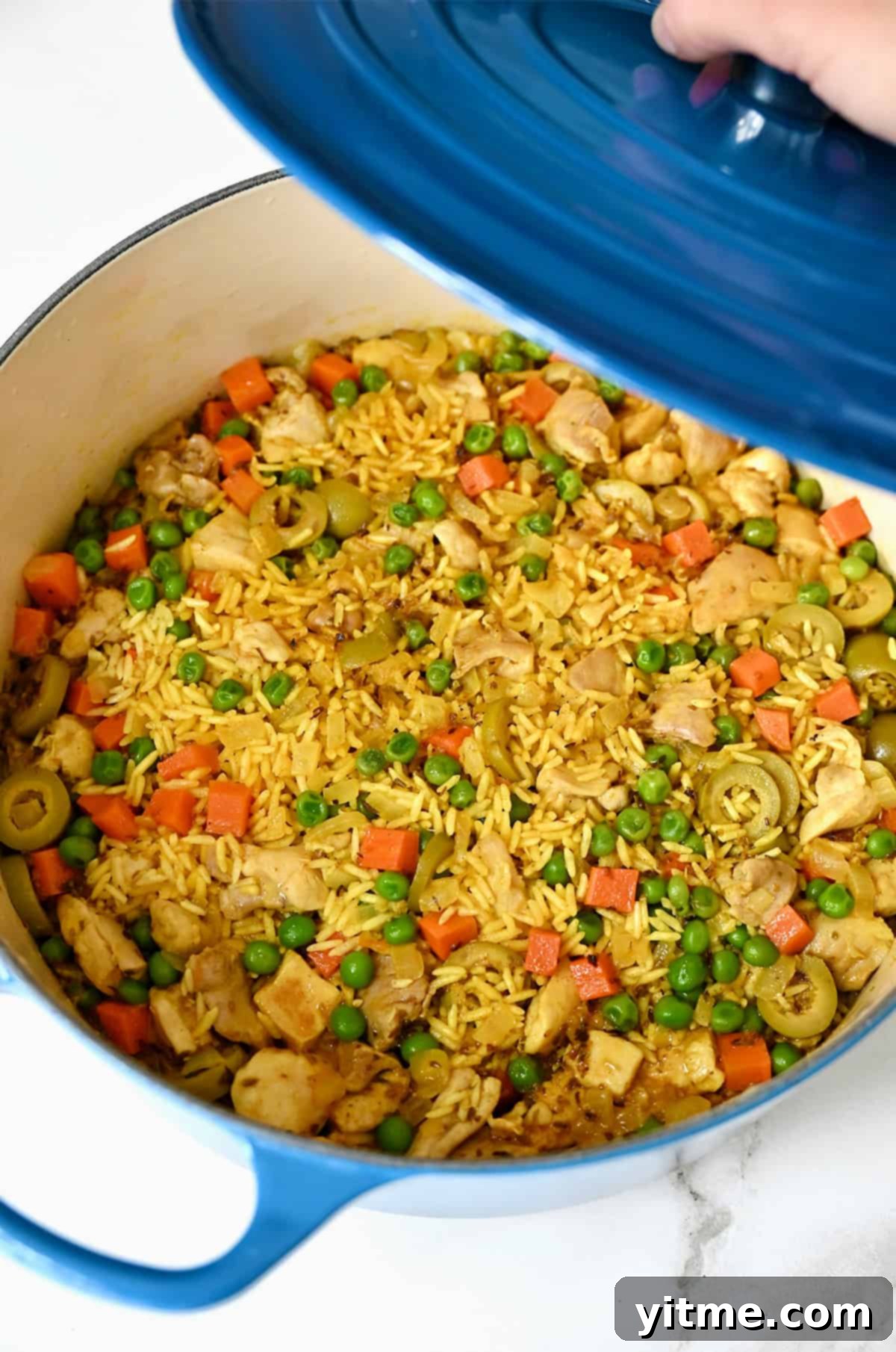 Arroz con pollo Cubano with veggies in a large heavy-bottomed stockpot.