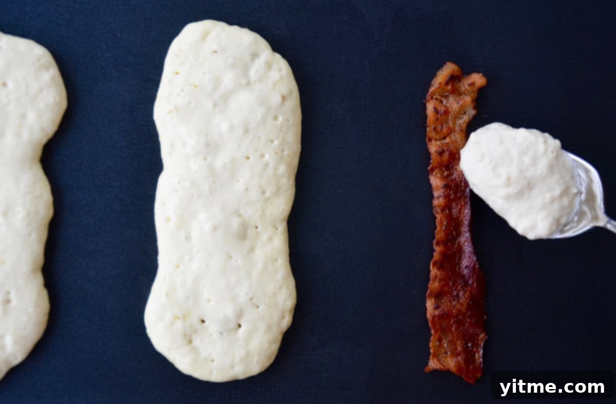 Golden Bacon Pancake Sticks 5 Spooning flapjack batter on top of bacon on griddle.