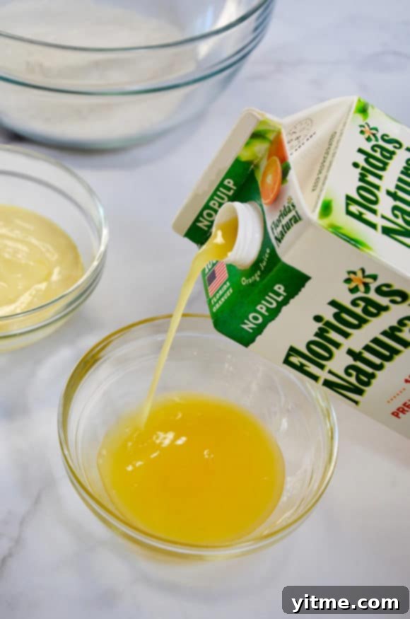 Carton of orange juice being poured into a glass bowl