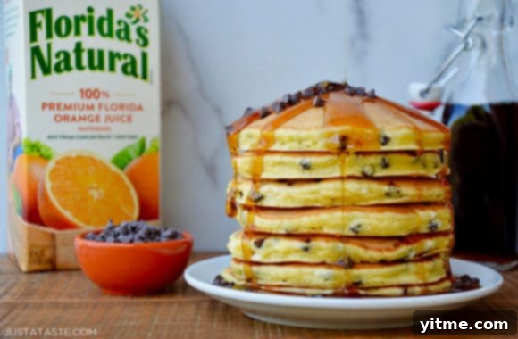 A plate of pancakes topped with chocolate chips and syrup