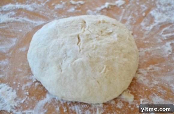 A ball of bread dough on a floured brown cutting board