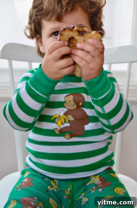 Child on chair holding a slice of banana bread up to his face