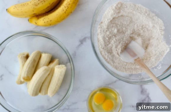 Various sized glass bowls containing halved bananas, flour mixture and eggs