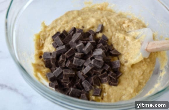 Spatula stirring chocolate chunks quick bread batter 