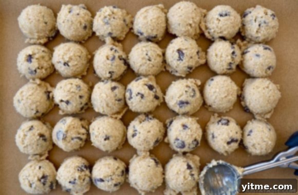 Cookie dough scoops on parchment paper with ice cream scoop