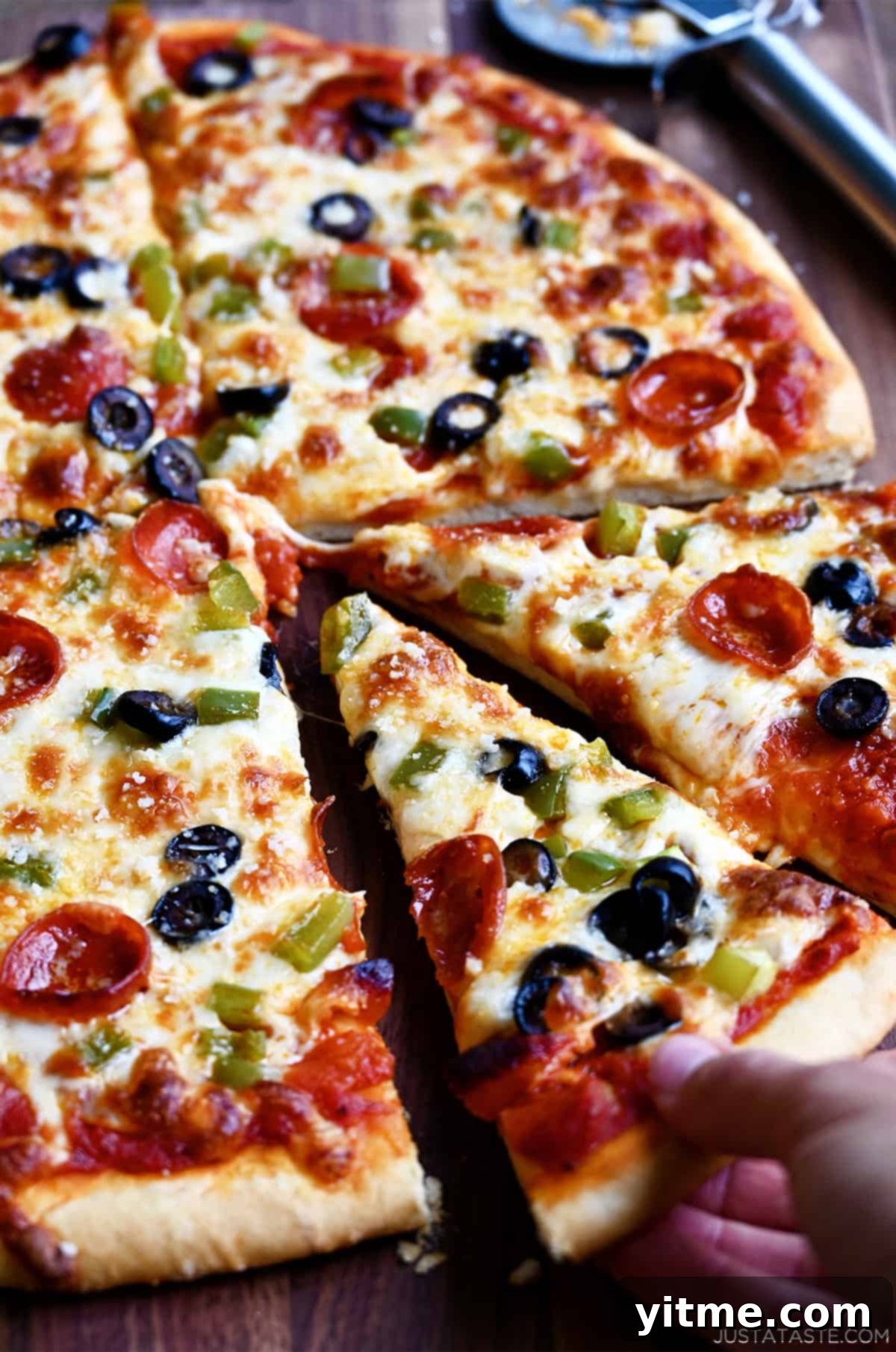 Freshly baked homemade pizza dough without yeast topped with melty cheese, mini pepperoni, sliced green peppers and black olives.