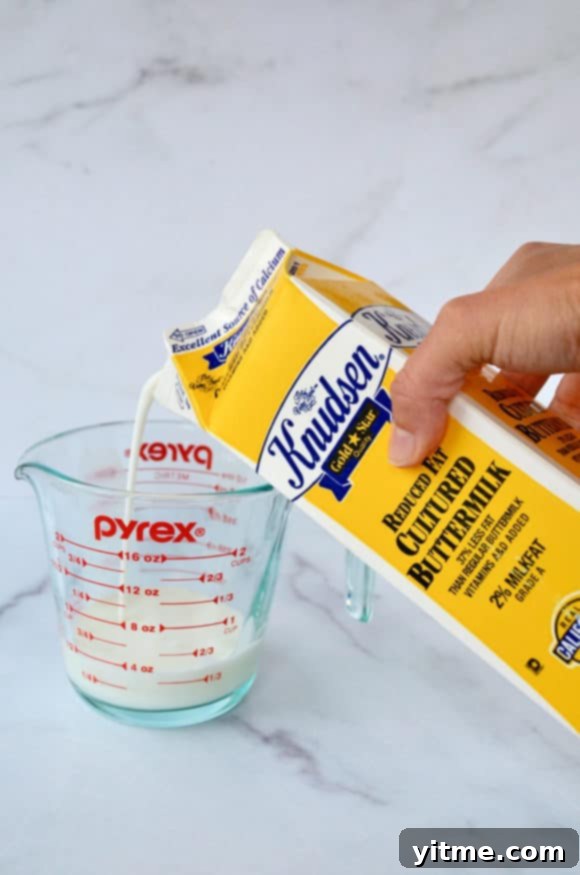 Top 5 Buttermilk Replacements 3 A carton of buttermilk being poured into a glass liquid measuring cup