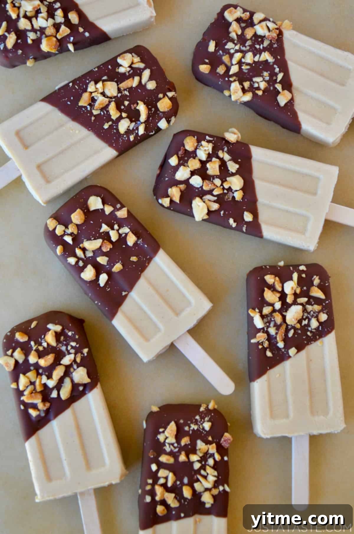 A top-down view of peanut butter frozen yogurt pops that have been dipped in chocolate and sprinkled with chopped peanuts.