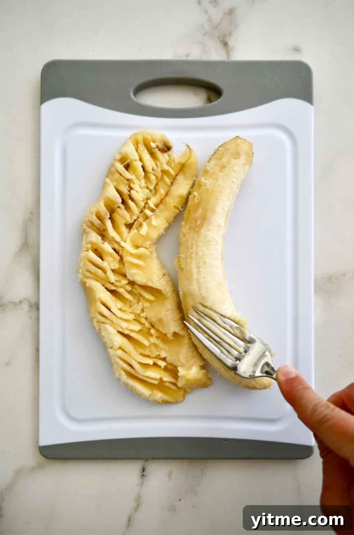 Mashing ripe bananas with a fork on a cutting board.